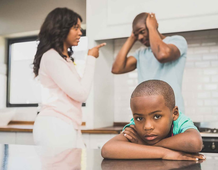 sad child crossing hands while parents argue